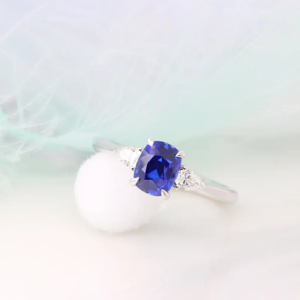 Royal Blue Sapphire Unheated with side Trilogy Pear Diamond Proposal Ring Perspective