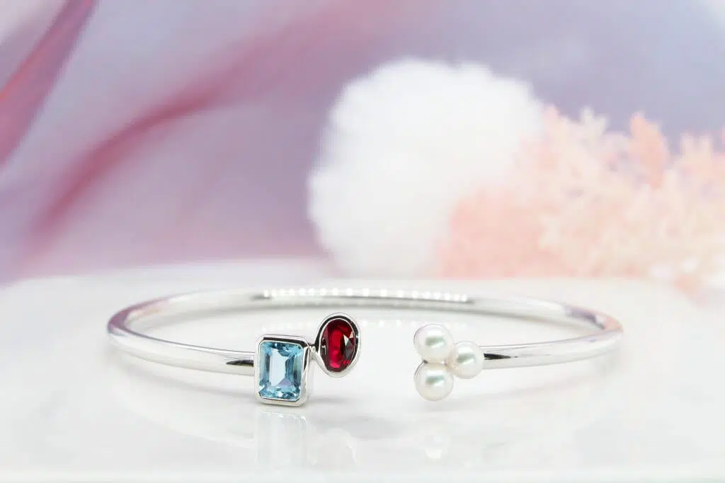 Customised Open Bangle with Coloured Gems( Ruby, Aquamarine and Akoya Pearl) and Pearl of individual family members birthstone. A customised family birthstone bangle designed by the gentleman for his beloved wife as a push present. Customised Push Present, Anniversary or unique Christmas gift for your special one at GIOIA Fine Jewellery.