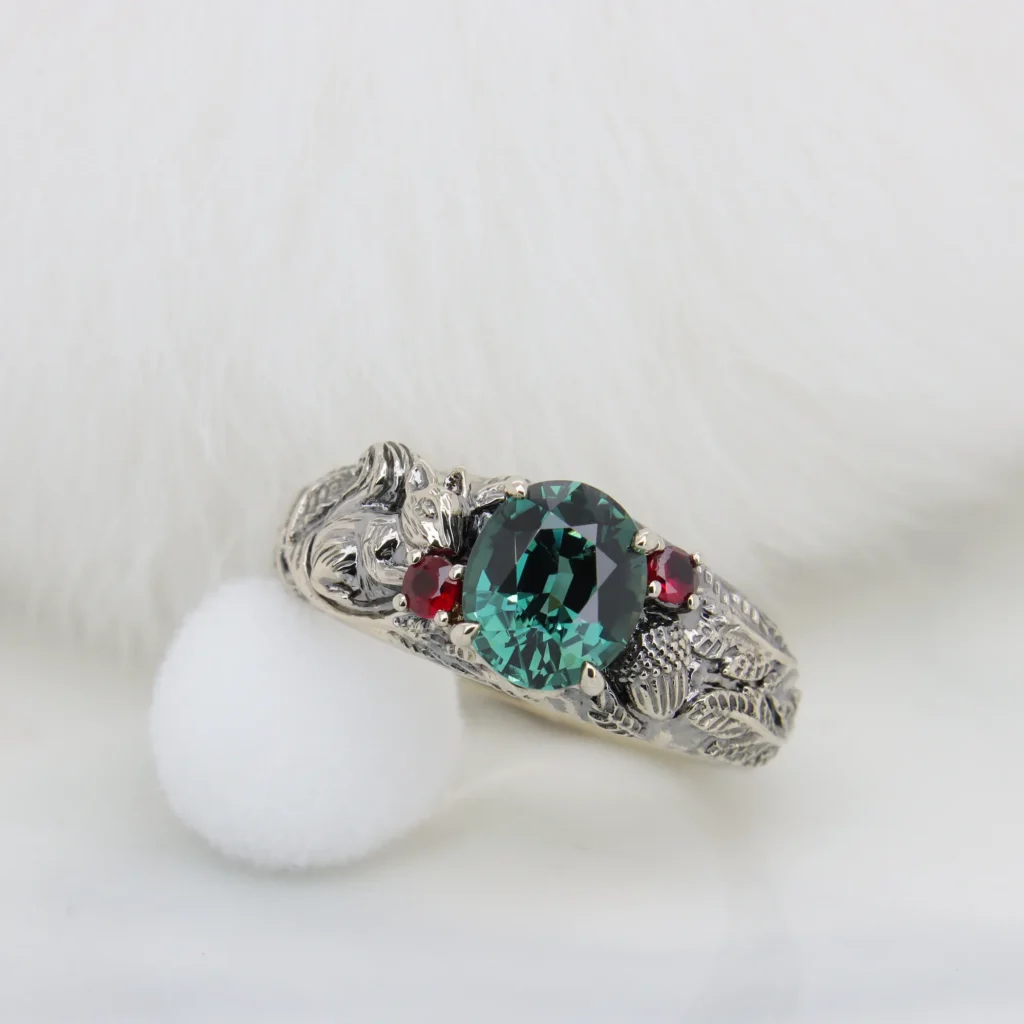 Teal sapphire squirrel ring in champagne gold with black plating, acorns and ruby side stones, by GIOIA