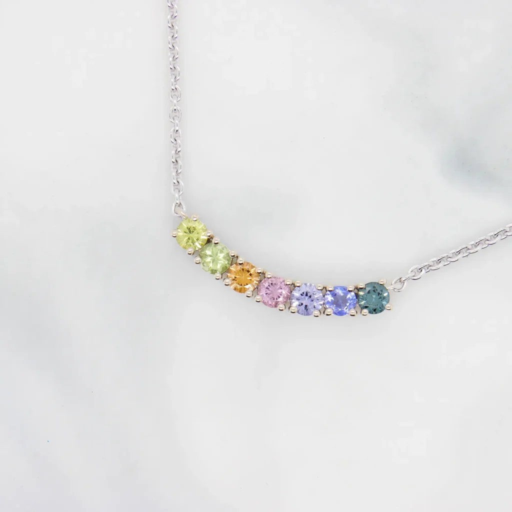 Curved necklace set with yellow sapphire, peridot, orange sapphire, pink spinel, violet spinel, tanzanite and teal spinel