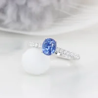 Personalised sapphire engagement ring in perspective, the oval blue sapphire raised in a four-claw setting above pave diamond shoulders, GIOIA Singapore