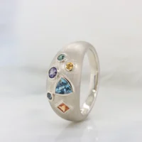 Multi-coloured gemstone dome ring in perspective, the scattered bezel-set cluster of aquamarine, sapphire, tourmaline and citrine across a brushed champagne gold dome, GIOIA Singapore